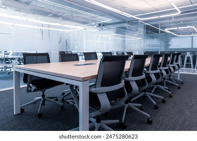Th showcases a modern, professional conference room setting.Room features a large wooden table surrounded by black mesh office chairs, indicating a space designed for meetings or collaborative work.  - Powered by Shutterstock