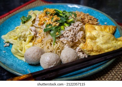 Thai Bamee moo dry egg noodles with wontons and pork balls on a turquoise plate