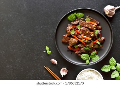Thai beef stir-fry with pepper and basil on plate on a dark stone background with copy space. Top view, flat lay - Powered by Shutterstock