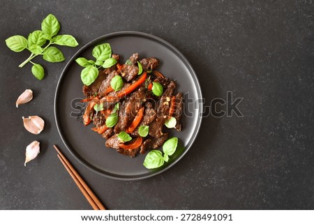 Thai beef stir-fry with pepper and basil on dark background with copy space. Top view, flat lay