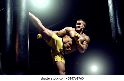 Thai boxer punch kick by punching bag, black bacground, horizontal photo - Powered by Shutterstock