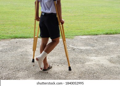 Thai boy student walking with crutches because of ankle sprained. Concept for physical pain. Accident injury from daily life activities.