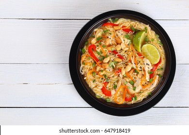 Thai Chicken Green Curry Paste Noodle Soup With Coconut Milk, Vegetables And Herbs In Black Bowl Sprinkled With Sesame Seeds And Peanut On Wooden Worktop, Authentic Recipe,view From Above