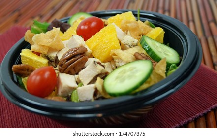 Thai Chicken Salad In A Takeout Bowl On Red Place Mat, Bamboo Background.  