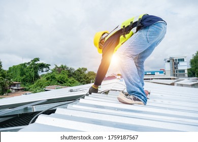 Thai Construction Worker Installing Metal Sheet On Warehouse Roof