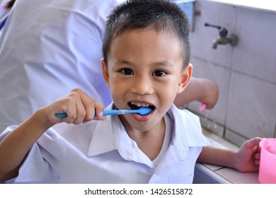 Thai Elementary School Students In Student Uniform Are Brushing His Teeth After Eating Lunch For Good Oral Health.