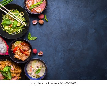 Thai food background. Dishes of thai cuisine. Tom yum, tom kha gai, pad thai noodles, fried rice with pork and vegetables khao phat mu, green papaya salad som tam, thai fruits. Space for text - Shutterstock ID 605651696