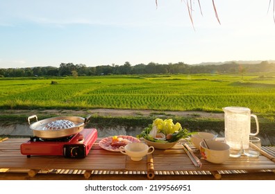 Thai Food. Thai Barbecued Pork On A Hot Pan With Various Vegetables. The Atmosphere Of The Rice Fields In The Evening.