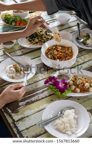 thai food on wooden table with people's hand enjoy eating it