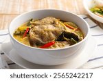 Thai Green Curry Catfish,Sliced catfish with green curry paste in coconut milk soup in white bowl.(kaeng kiew waan ikan keli)