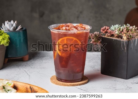 Thai lemon tea served in disposable glass with lime slice isolated on wooden board side view of taiwanese ice drink