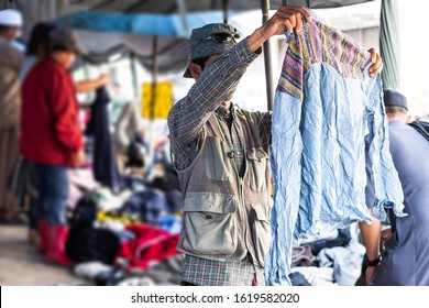 Thai Man Is Choosing Used Second Hand Clothes At Flea Market In Thailand