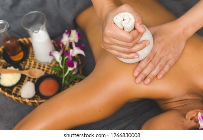 Thai Massage of  asian woman in spa room. Beautiful young woman having massage with herbal compress balls in therapy spa salon. - Powered by Shutterstock