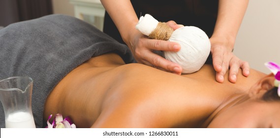Thai Massage of  asian woman in spa room. Beautiful young woman having massage with herbal compress balls in therapy spa salon.