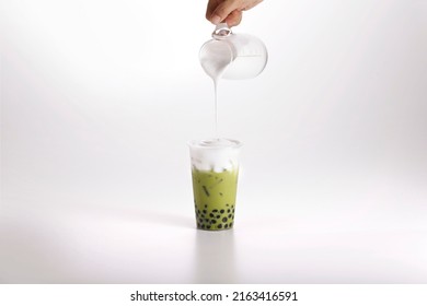 Thai milk foam cream cheese green tea. Thailand bubble tea tapioca pearls with hand pouring milk foam on white background