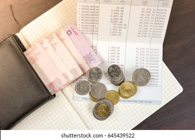 Thai Money And Bank Saving Account Book On Wooden Table, Money Savings Concept