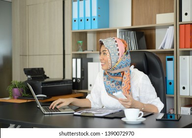 Thai Muslim Women Sitting In An Office With A Computer, Phone For Customer Contact And Many Office Equipment.