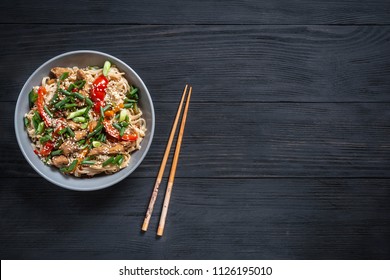 Thai noodle and chicken plate on a black wooden background with Chinese chopsticks and copy space - Powered by Shutterstock