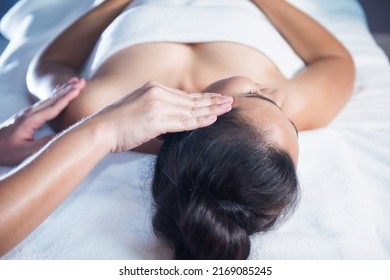 Thai Oil Ayurvedic Face Massage On Bed To Asian Woman By Professional Masseuse. Anti-aging Facial Treatment In Spa Salon. Girl With Alternative Medicine Therapy.