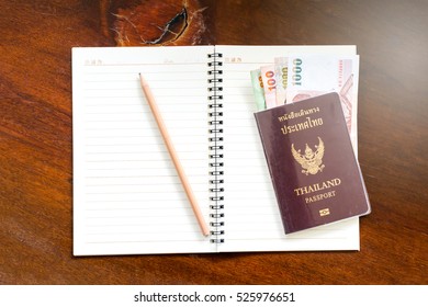 Thai Passport with Thai money banknote for travel.The passport of Thai citizen and Thai banknote on wood  background. 