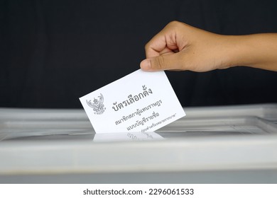 Thai people drop their ballot papers into the box to vote for members of the House of Representatives. The ballot papers are written in Thai,meaning Party-list proportional representation ballot paper - Shutterstock ID 2296061533