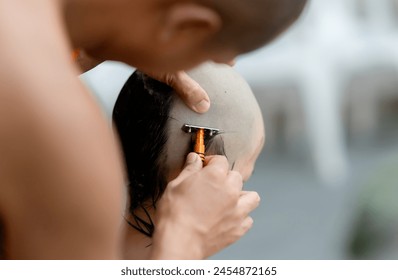 Thai people shave their hair and eyebrows with a razor and hold a light in preparation for ordination as a monk. - Powered by Shutterstock