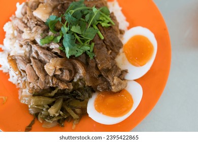 Thai pork leg pot stewed with rice and boiled egg on a orange dish. Street food Thai. - Shutterstock ID 2395422865