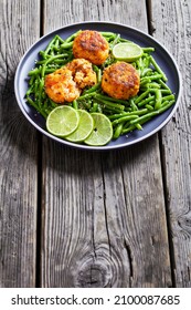 Thai Prawn And Crab Cakes On A Plate With Boiled Green Beans, Lime On A Wood Table, Vertical View From Above