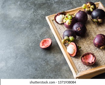 Thai queen of fruits - Mangosteen is  Organic fruit on the wooden tray. Fresh mangosteens on grey background. Selective focus. Copy space