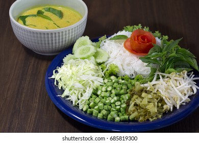 Thai Rice Noodle Eaten With Curry And Veg. Thai Food (Thai Language Kanom Jeen) On Blue Dish And Green Bowl, All On Brown Wooden Background / Selective Focus

