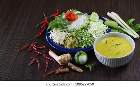 Thai Rice Noodle Eaten With Spicy Curry And Veg. Thai Food (Thai Language Kanom Jeen) On Blue Dish And Green Bowl, All On Brown Wooden Background / Still Life AndSelective Focus 

