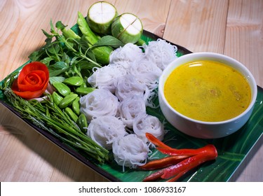 Thai Rice Noodle Eaten With Spicy Curry And Veg. Thai Food (Thai Language Kanom Jeen) On Blue Dish And Green Bowl, All On Brown Wooden Background / Still Life AndSelective Focus 

