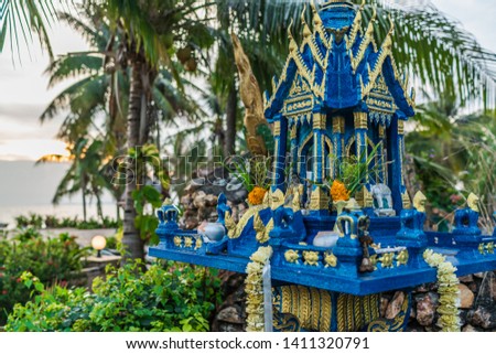 Thai spirit house blue yellow color with palms and sea view