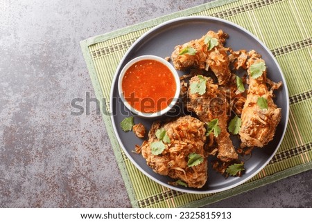 Thai Street Food Hatyai Fried Chicken with sweet chili sauce and crispy onions close-up on a plate on the table. Horizontal top view from above
