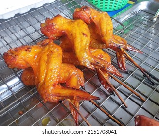 Thai style grilled chicken wings in skewers on stainless steel tray, selling at a shop, street food in Thailand.
