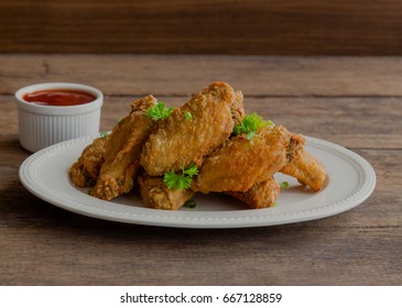 Thai style homemade deep fried chicken wings on white plate served with barbecue dipping sauce or tomato sauce(ketchup) so delicious and crispy. Street food.