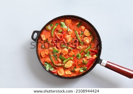 Thai style red chicken curry with vegetables in pan over light stone background. Top view, flat lay