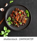 Thai style stir-fry beef with vegetables over black stone background. Top view, flat lay