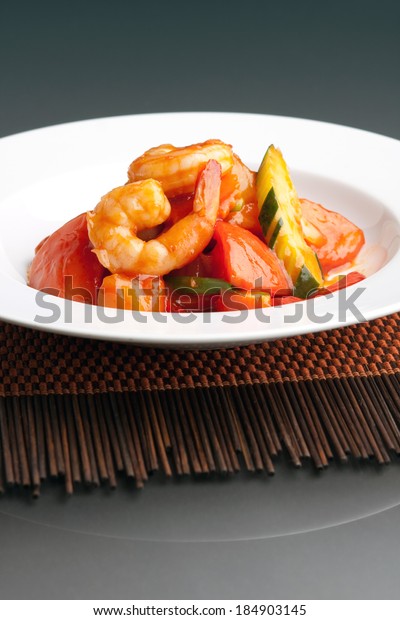 Thai style sweet and sour shrimp dish\
presented beautifully on a round white\
plate.