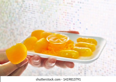 Thai Traditional Dessert, Hand Holding Golden And Sweet Egg Yolks Or Rice Flour And Glutinous Flour Dumplings With Egg Yolks Cooked In Syrup.