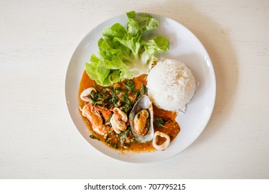 Thai traditional food : Khao Pad Kra Pao, Stir-fried sea food and basil leaves. Served with rice. (Selective Focus)