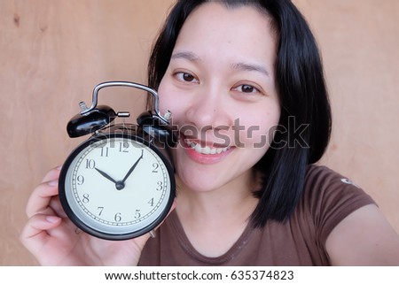 Thai woman holding alarm clock