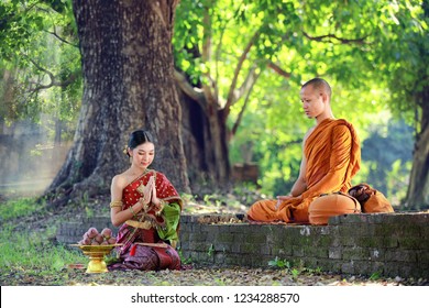 Thai woman with traditional dress sit pray respect monk under big tree in forest , present buddhism people Make merit with monk that representative
of Buddha. Woman Make merit by offering food to monk - Powered by Shutterstock