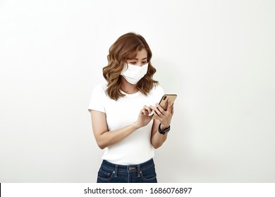 Thai woman wearing a face mask using the smartphone isolated on bright gray background, Flu epidemic, dust allergy, protection against virus. City air pollution concept - Powered by Shutterstock