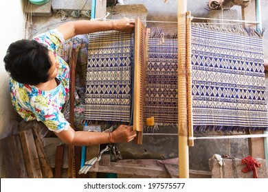 Thai woman weaving traditional straw mat using Cyperus alternifolius stems, Khon Kaen, Thailand