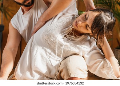 Thai Yoga Upper Body Passive Stretching Massage. Female Patient Receiving Relaxing Spinal Twist, Thai Massage Pose That Stretches The Back On Each Side Of The Body.