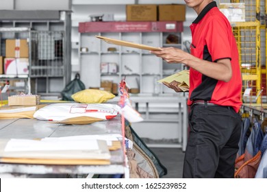 Thai Young Postal Man Is Sorting Mail Parcels At Postal Office.