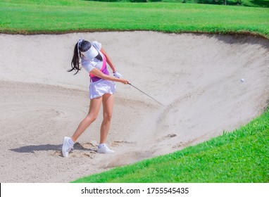 Thai young woman golf player in action swing in sand pit during practice before golf tournament at golf course