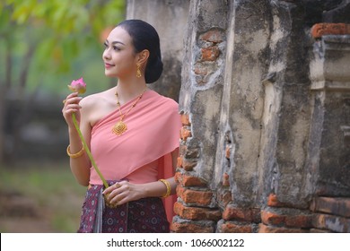 Thai young woman portrait in Thai traditional dress at historical park, there is a lotus in here han, Ayutthaya, Thailand.