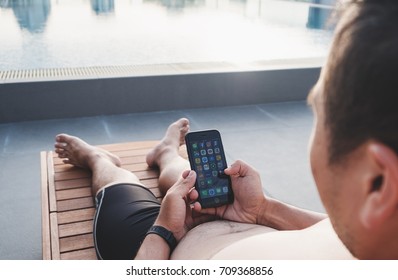 THAILAND - 2 SEP - Asian Man Holding Iphone Mobile Smart Phone, While Laying Down On Sunbath Lounge Chair At Resort Swimming Pool, For Relax In Weekend At Pattaya, Thailand On September 2, 2017